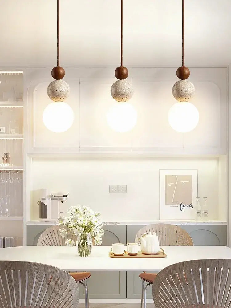 Three cream style led pendant lamps with matte brown tops and textured concrete spheres on copper cords for decorbites bedroom decor