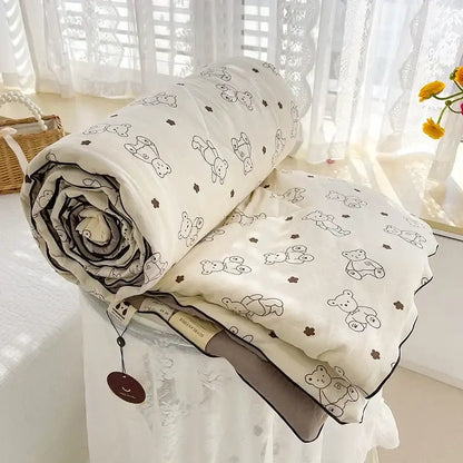 A cream teddy bear breathable double gauze quilt with black outlined bears and brown flowers, dark gray stitched edges