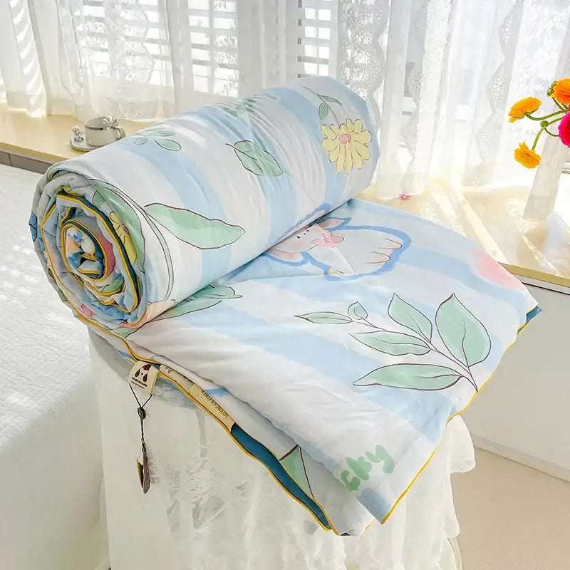 A soft light blue breathable double gauze quilt with pastel floral and leaf patterns for bedroom bedding decorbites