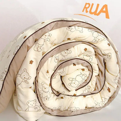 A cream teddy bear double layered soya fibre quilt rolled up featuring outlined bears and small brown flowers