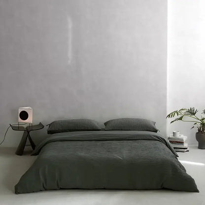 Dark gray ribbed duvet cover set with matching pillows on a minimalist bed featuring cotton foam yarn bedding set