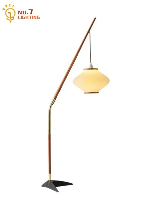 A sleek floor lamp with a curved wooden and brass frame and amber glass shade for decorbites cream wind acrylic decor