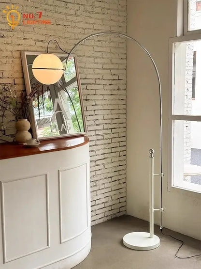A cream wind floor lamp with a sleek arched chrome frame and warm-toned glass globe shade for decorbites cream wind