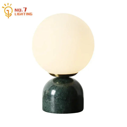 A decorbites cream wind table lamp with a spherical glass off-white globe and dark green cream wind marble base