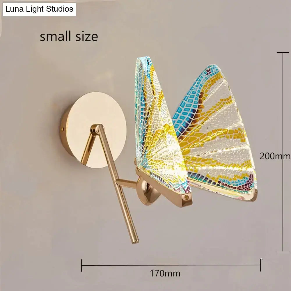 A creative colorful butterfly led wall lamp with gold finish and mosaic yellow blue and white glass wings for bedroom use