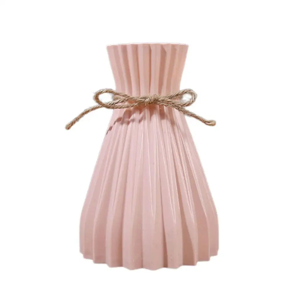 A blush pink pleated ceramic flower bottle type vase with a rustic twine bow designed for dry flower display