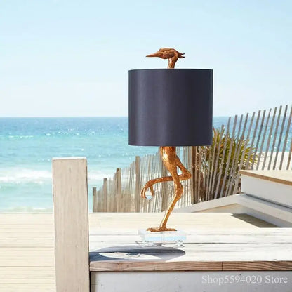 Golden bird-shaped table lamp with black shade and clear glass base for bedroom decor by decorbites creative ostrich table
