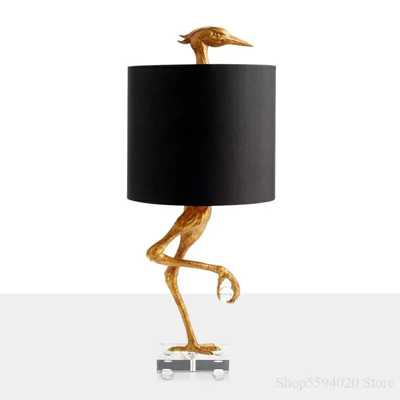 Golden bird-shaped creative ostrich table lamp with black cylindrical shade and clear acrylic base for bedroom decorbites