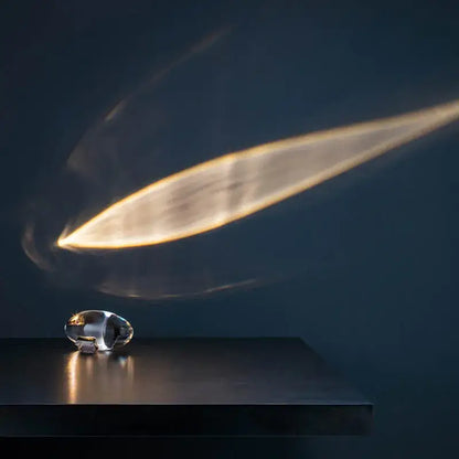 A sleek transparent crystal eye sky led table lamp with metallic accent on dark surface for bedroom decorbites table lamp