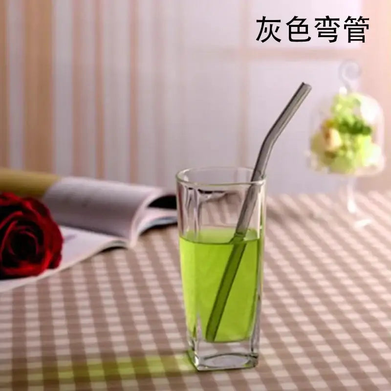 Gray bent metal drinking straw shown with a curved amber glass drinking straw kitchen accessory