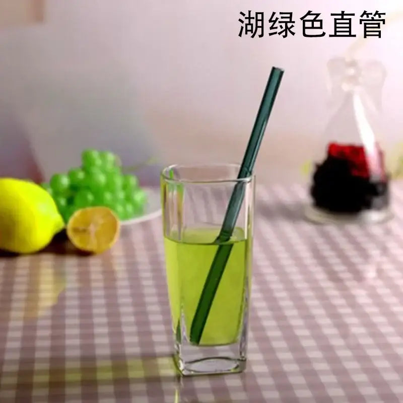 A sleek dark green glass drinking straw with a smooth straight design in a glass of light green liquid