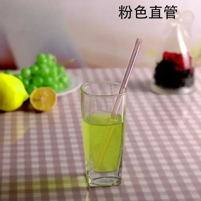 A translucent pink glass drinking straw in a tall clear glass with green liquid showcasing a kitchen accessory