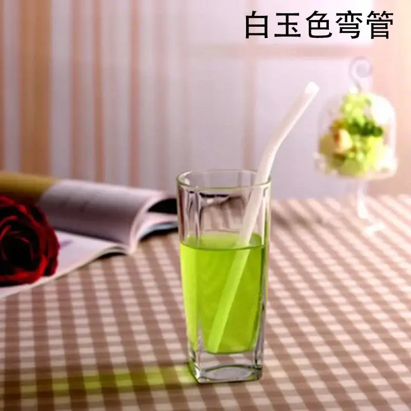 White curved glass drinking straw with green liquid in clear glass for kitchen accessory use