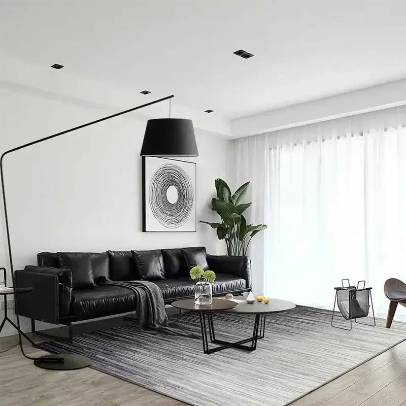Black leather sectional sofa with plush cushions paired with curved matte black led floor lamp for living room lighting