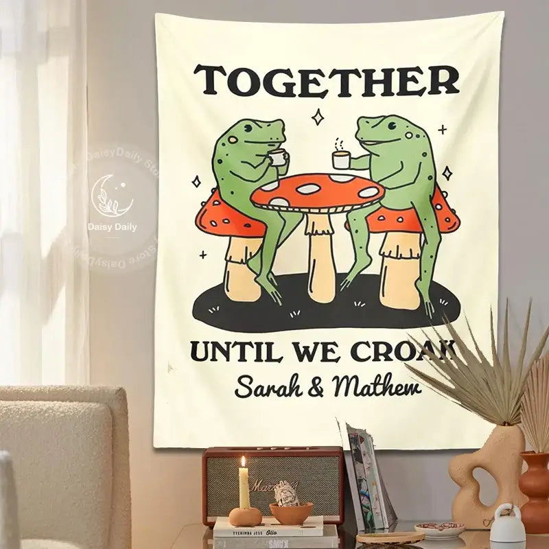 Cream-colored wall tapestry with cute cartoon frog moon design of two green frogs on red mushrooms sipping tea together