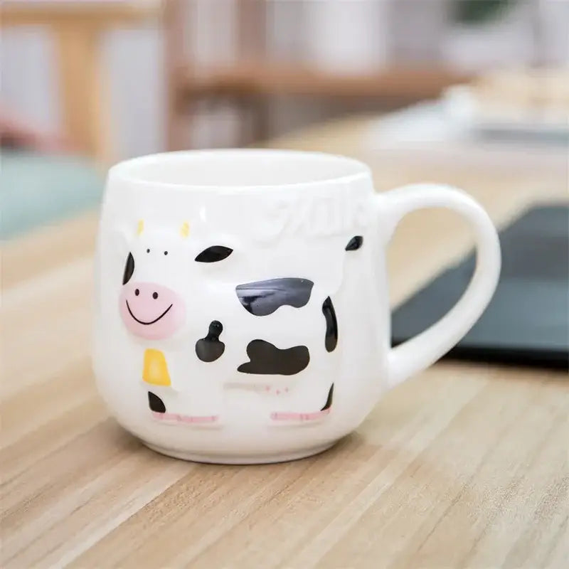 White and black cow ceramic mug by decorbites featuring a cheerful cartoon cow with yellow collar for coffee use