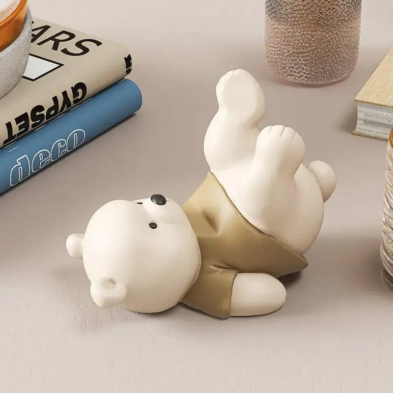 Cute cream ceramic bear cellphone stand featuring a white bear figurine wearing beige shorts lying on its back