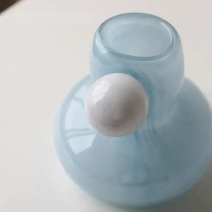 A translucent light blue glass candle holder with a glossy white spherical accent for decorbites cute glass decor