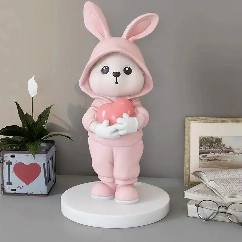 Cute pink rabbit desk figurine wearing a hooded outfit and holding a heart for home decor and rabbit desk use