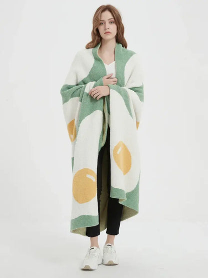 A cozy green knitted throw blanket with a plush cute poached egg pattern perfect for bedroom decorbites decor