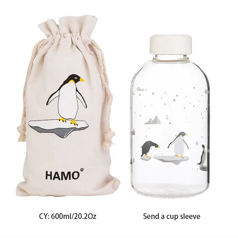 Clear glass decorbites blue glass water bottle with white cap and penguin design with matching beige drawstring bag