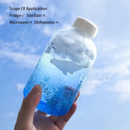 Clear plastic water bottle with white cap featuring illustrated seal in blue liquid and aquatic plants decorbites blue glass water