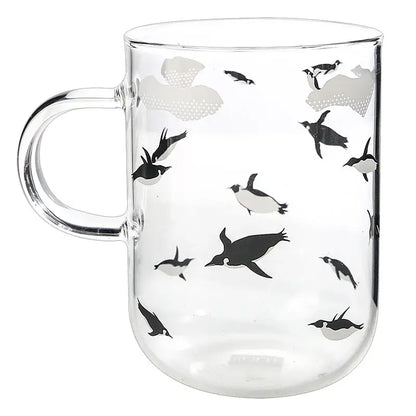 Clear glass coffee mug featuring a playful black and gray penguin pattern heat resistant for tea and coffee use