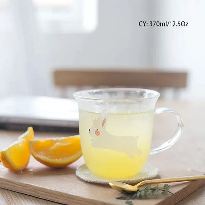 Clear glass coffee mug with a cute white bunny design and transparent handle filled with yellow liquid for tea or coffee