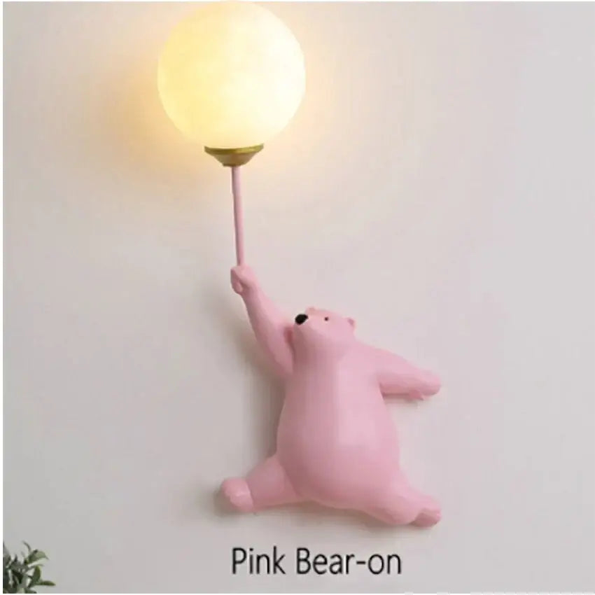 Pink bear wall lamp featuring a warm-toned round globe light held by its outstretched paw for bedroom use