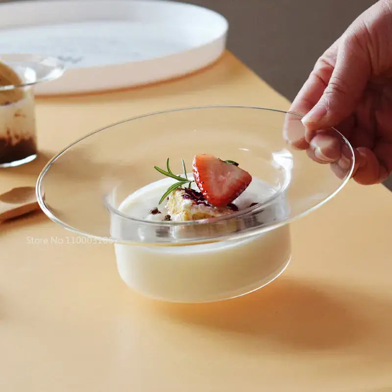 Cute straw hat glass bowl by decorbites holding creamy white pudding topped with strawberry and rosemary garnish