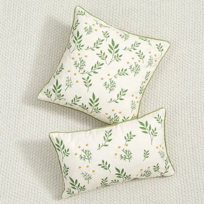 Cream cushion cover with daisy floral embroidery featuring green leaf and yellow dot patterns and olive-green trim by decorbites