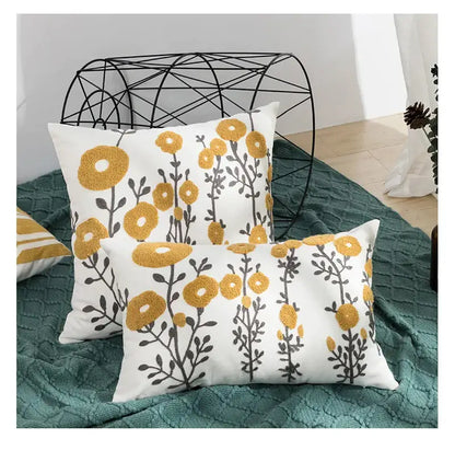 White throw pillows with embroidered yellow and gray daisy floral geometric embroidery for living room decor by decorbites