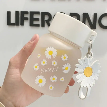 A frosted pink decorbites daisy flower glass water bottle with white lid and sweet cursive script for kitchen decor