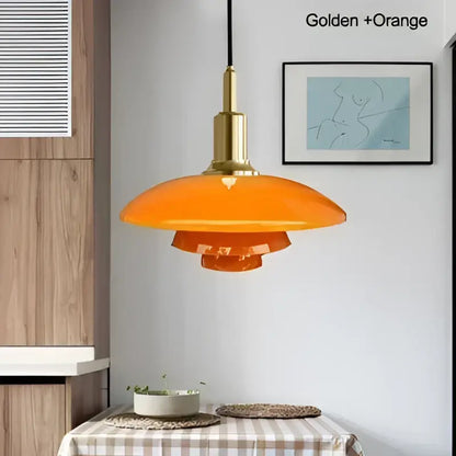 Orange glass pendant light with frosted tiered design and golden brass fixture as a dining room focal point