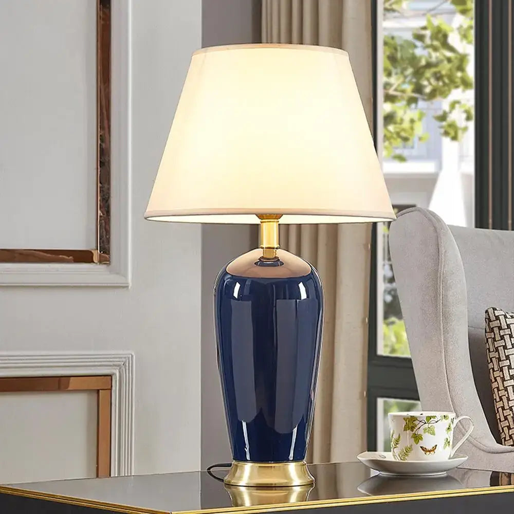 Dark blue ceramic table lamp with remote control, gold-toned base, and cream fabric shade by decorbites for bedroom decor