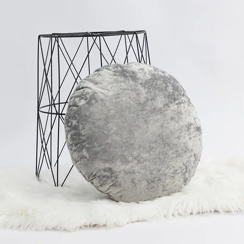 A dark grain velvet pillow cover in gray with a plush textured surface on a white faux fur rug for decorbites decor