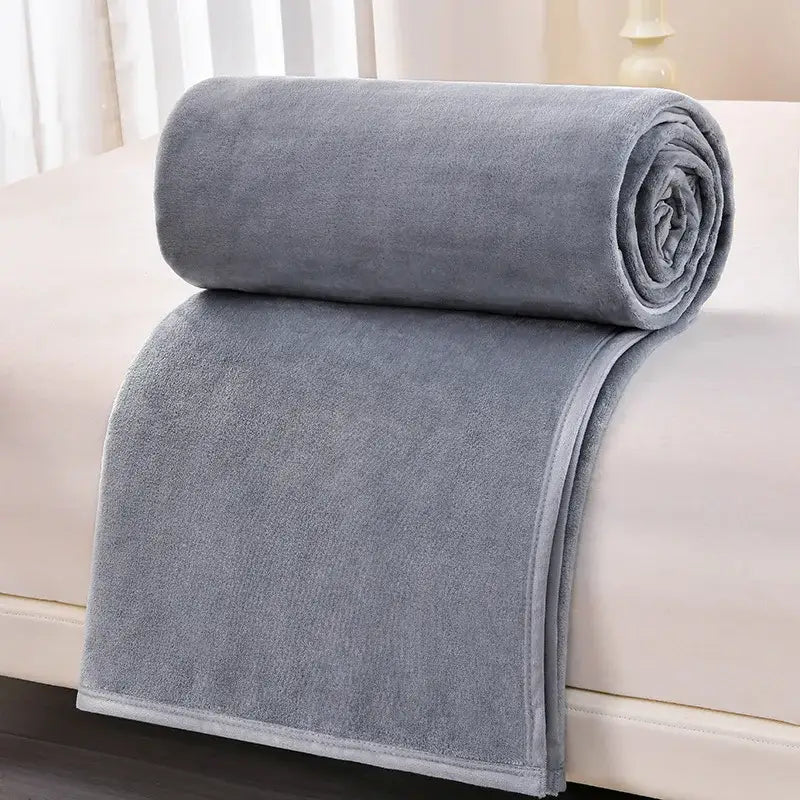 A dark gray and light gray decorbites cozy flannel blanket made of soft plush fleece neatly rolled on a bed