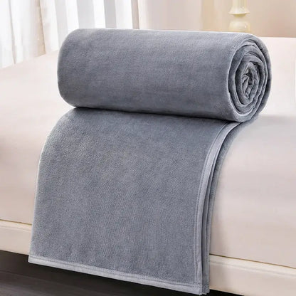 A dark gray and light gray decorbites cozy flannel blanket made of soft plush fleece neatly rolled on a bed