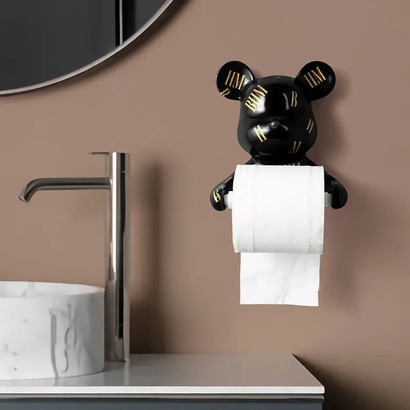 Dark green resin paper towel holder shaped like a black bear with gold lettering holding white toilet paper