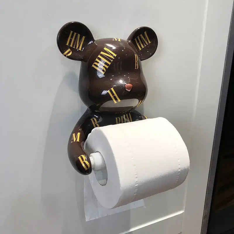 Brown bear-shaped resin paper towel holder with gold hm lettering and glossy finish holding white toilet paper roll