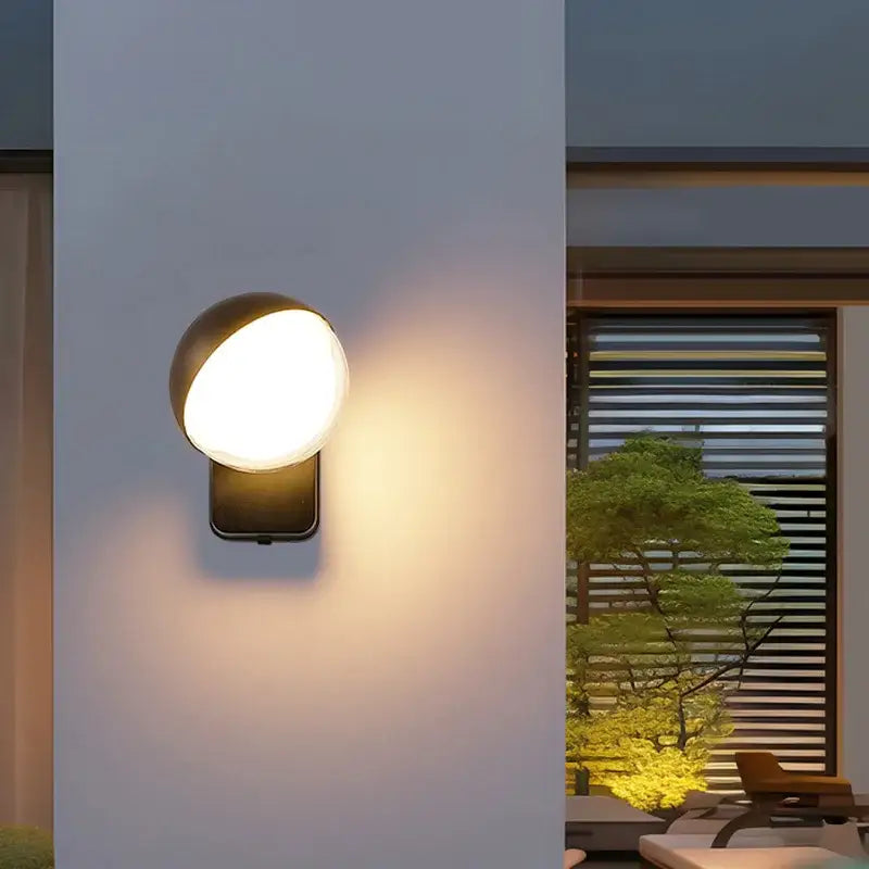 Modern black motion sensor wall lamps with a sleek rounded globe light fixture emitting warm illumination