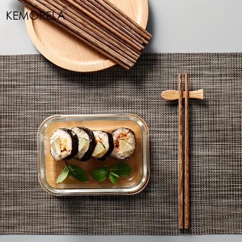 Set of natural wooden chopsticks with fish-shaped rest beside sushi container enhancing dining experience
