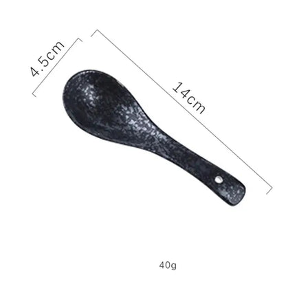 Black ceramic rice spoon with speckled texture and handle hole included in DecorBites™ retro ceramic ramen bowl set