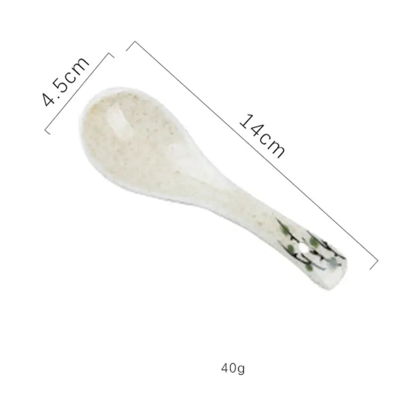 A delicate white ceramic spoon with speckled finish and green floral design for the decorbites ceramic ramen bowl