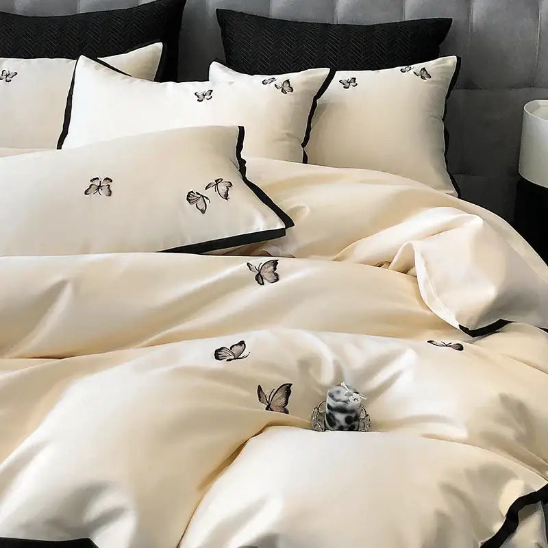 Cream-colored satin 600tc egyptian cotton bedding set with black butterfly embroidery and contrasting black piping