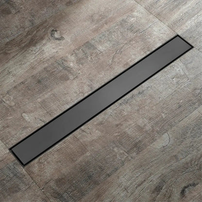 Black rectangular floor drain with sleek modern design embedded in gray wood grain tile for rose gold bathroom use