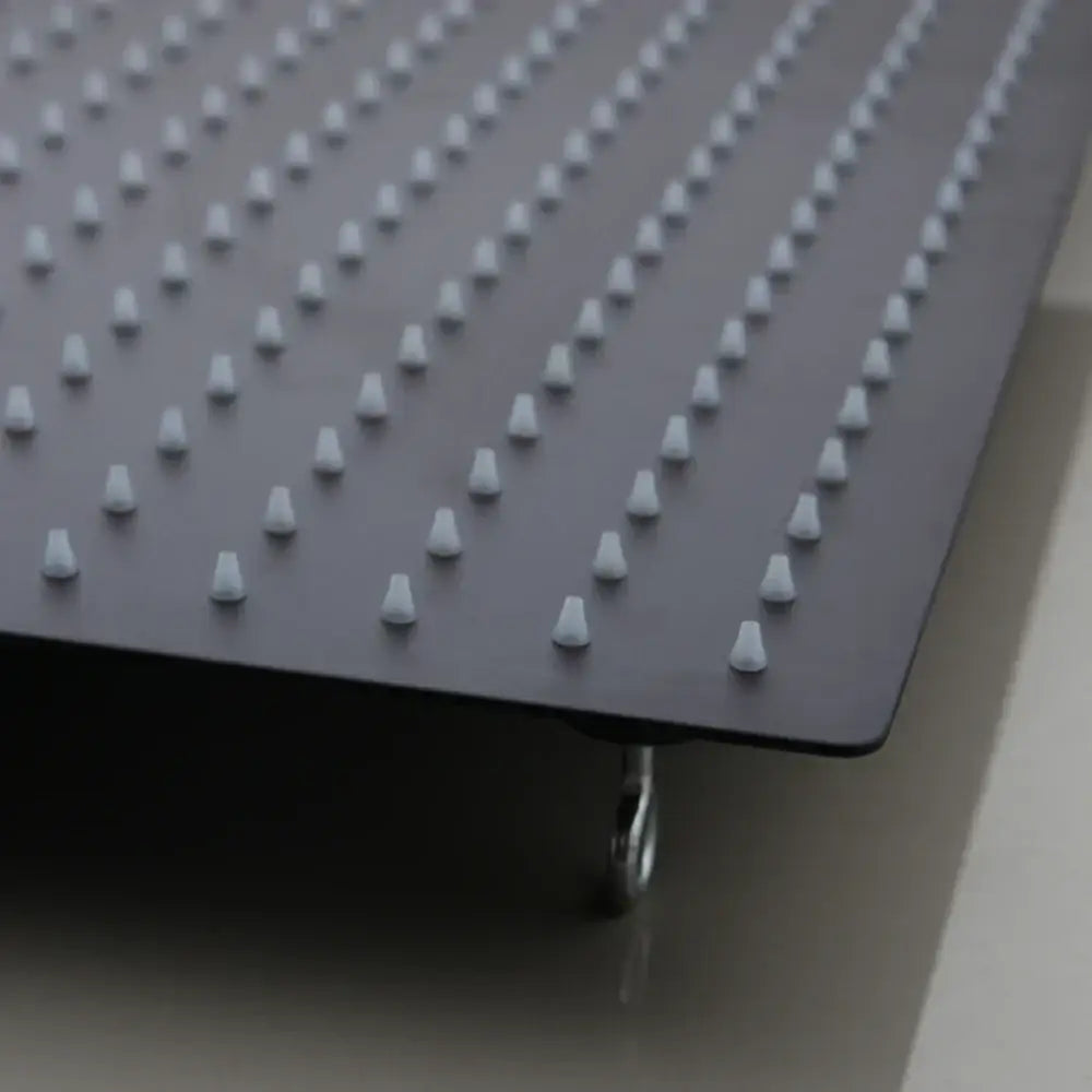 Black ultra-thin rain shower head with white plastic pegs and metallic caster wheel shown from the back side