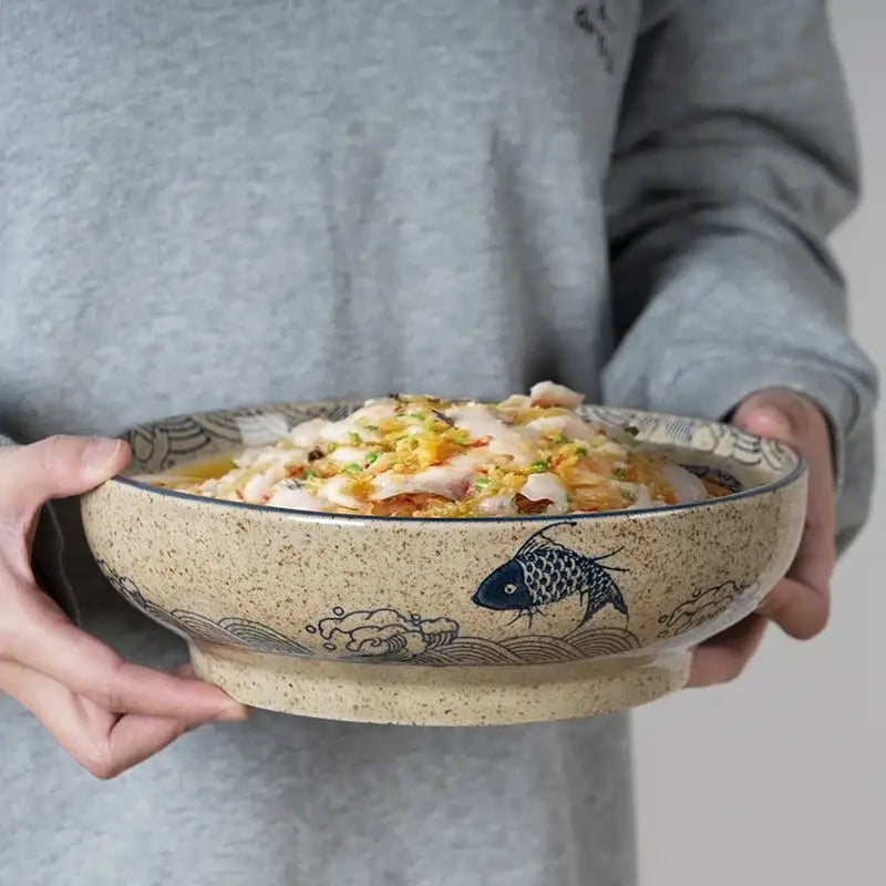 Beige retro ceramic ramen noodle bowl with blue fish and wave patterns holding steamed fish dish for soup serve