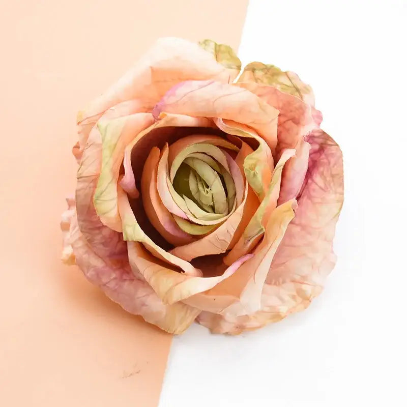 A delicate peach and blush pink 9cm silk roses artificial flowers with subtle green undertones for home decor and weddings