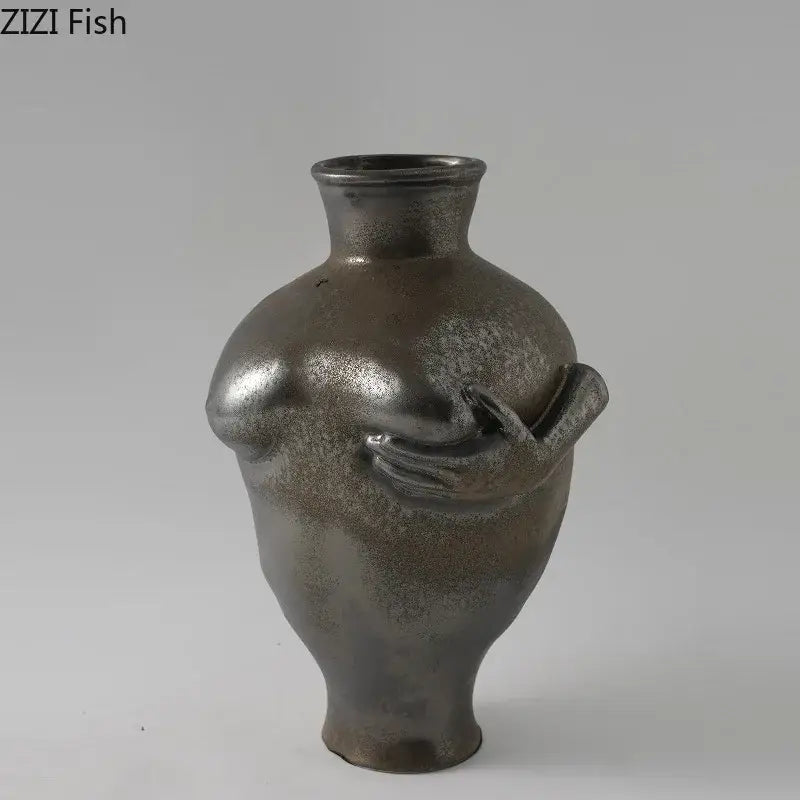 A sleek metallic gray decorbites abstract art ceramic vase featuring a sculpted torso and hand holding a small object